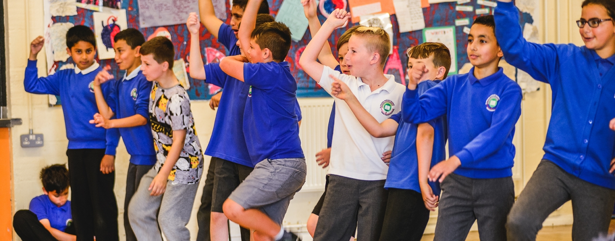 WNO Schools Workshops Kirsten McTernam A gruup of school children arms raised in play or performance.