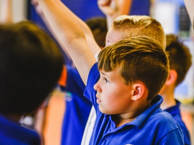 glyncoedcansingkirstenmcternan 192 Kirsten McTernan A side profile of a school boy in bright blue polo shirt holds his hand high making a fist.