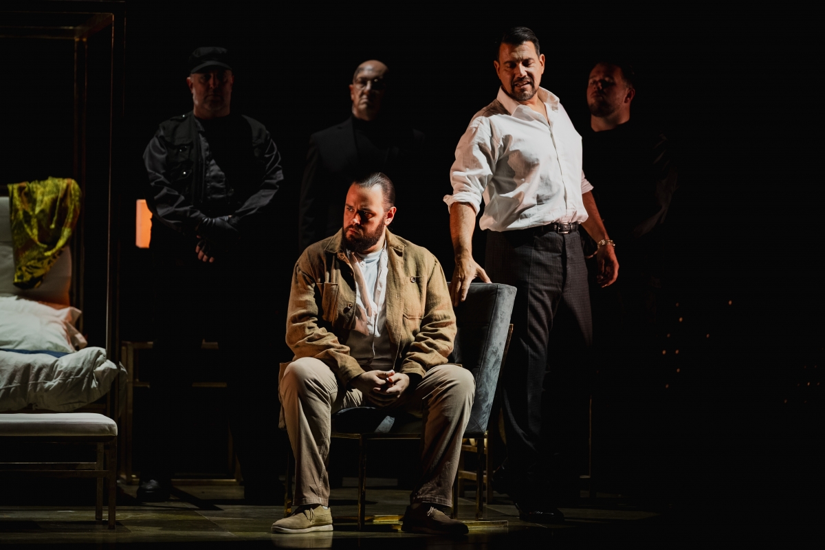 WNO Tosca Andrés Presno Cavaradossi Dario Solari Scarpia Photo Credit Dafydd Owen 1152 Cavaradossi sits on a velvet chair, staring angrily to his right. Scarpia, dressed formally, stands to his left, his hand upon the chair and a sinister expression on his face. His three henchmen stand behind.