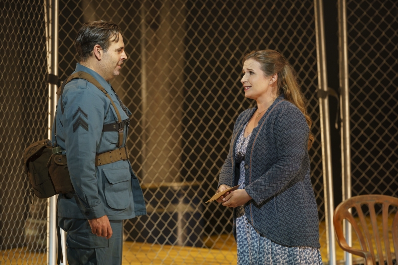 Man in uniform talks to a hopeful looking lady clutching a letter