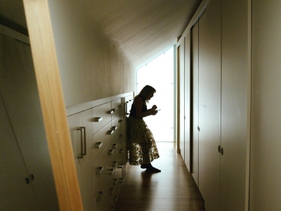 Woman standing in slumped posture between cupboards and wardrobes 