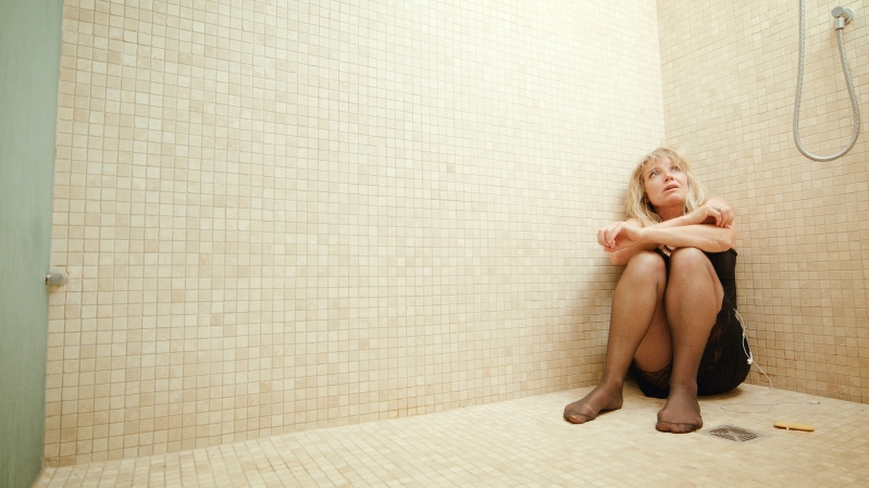 Woman sitting on floor of shower looking up