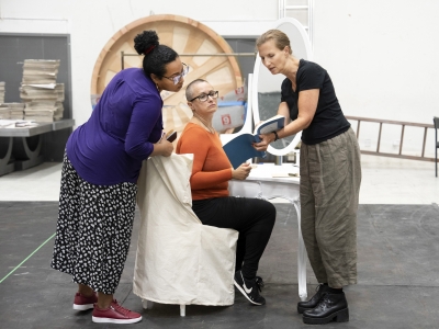 three women consult the script, one sat, two standing