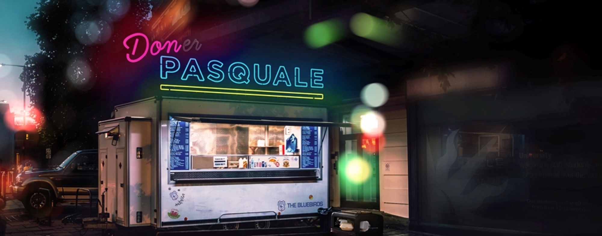 WNO Don Pasquale Cover Image ART 1000x486px RGB Brightly-lit shop in the dappled evening light, with 'Don Pasquale' in pink and blue neon lights.