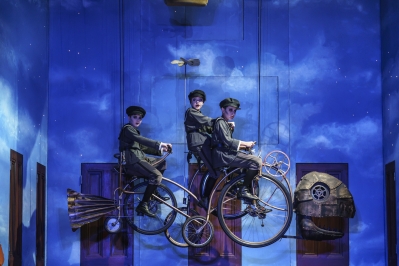 Three boys on bikes with fish head and tale cycling through the air.