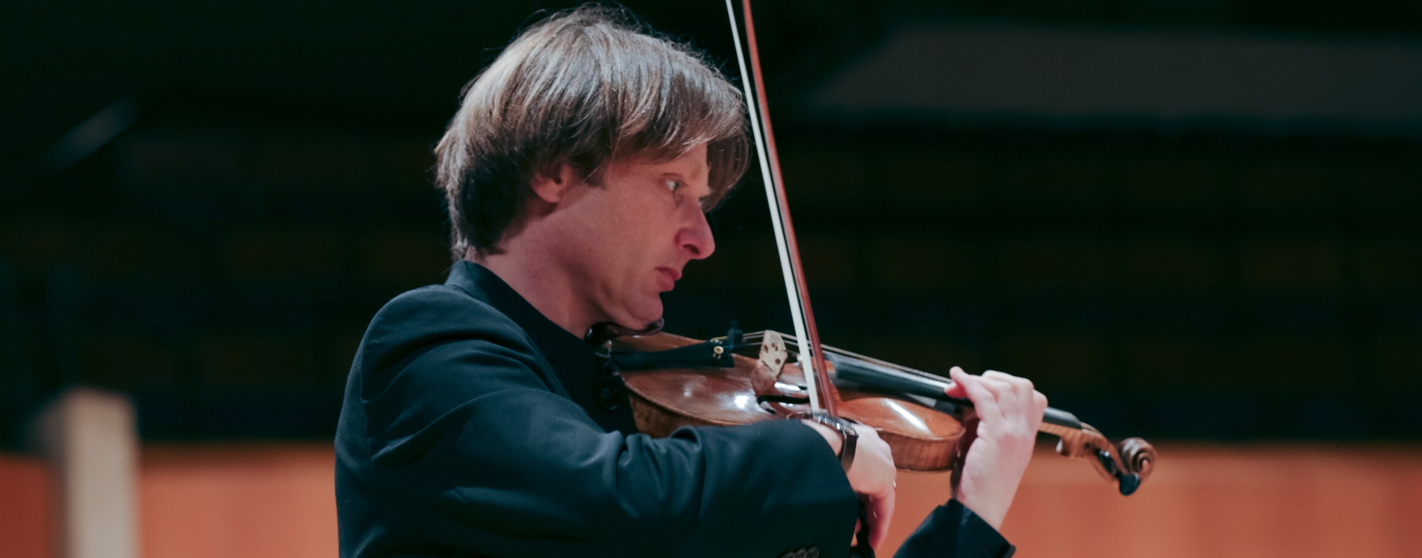 A man in a black jacket plays violin.