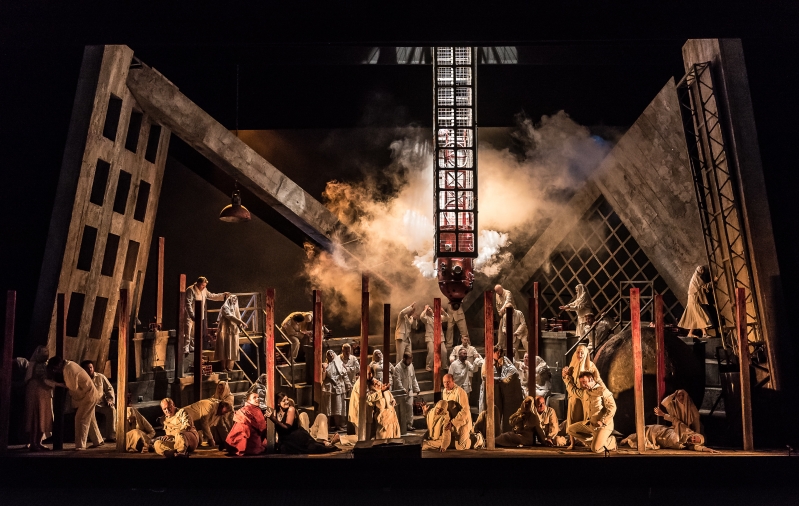 Wide shot of stage smoke and grated scenery and lots of people onstage.