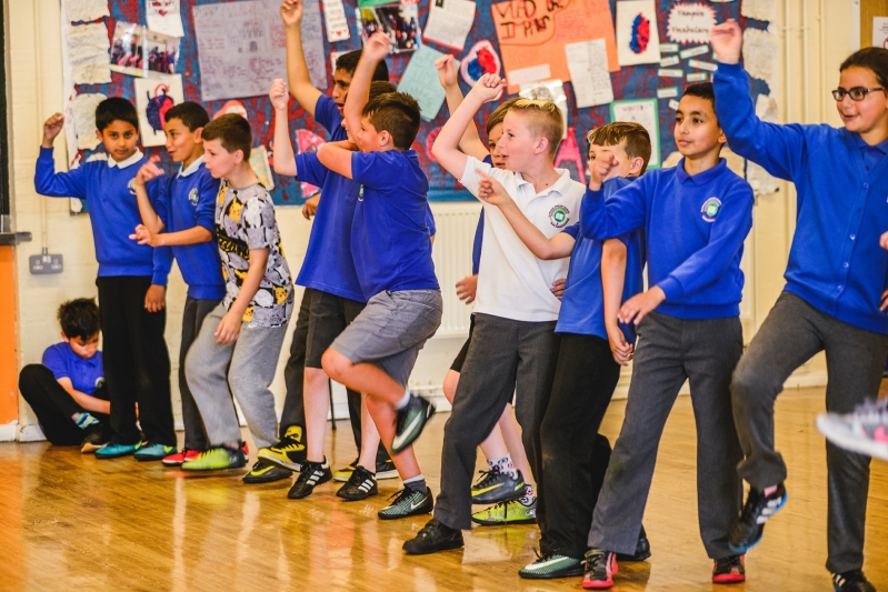 WNO Schools Workshops Kirsten McTernam A gruup of school children arms raised in play or performance.