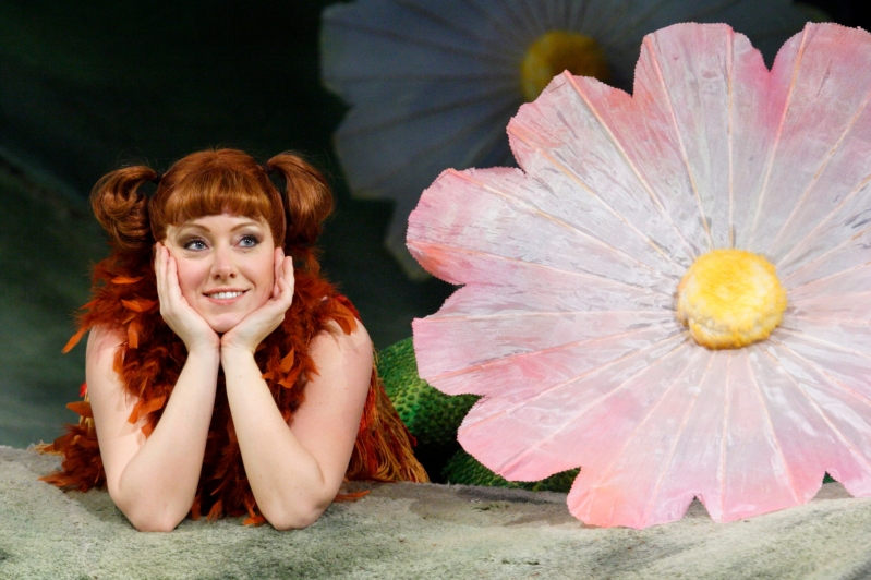 Vixen laying down next to large flower with hands on chin